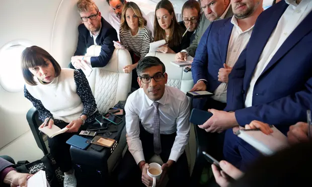 The prime minister Rishi Sunak huddling with political journalists onboard a government plane bound for Washington