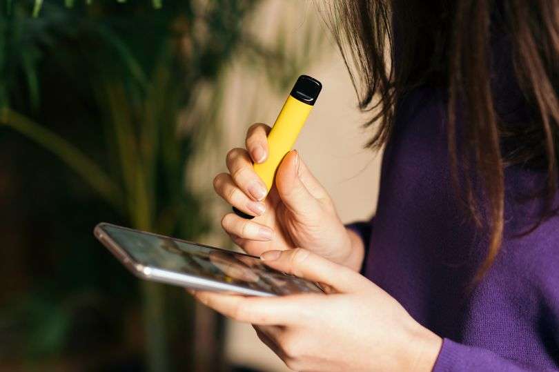 Yellow disposable electronic cigarette in a womans hand