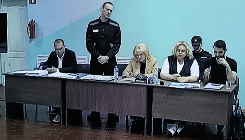 A view of a TV Screen showing Russian opposition leader, Alexei Navalny, 2nd left, between his lawyers in a courtroom, during a preliminary hearing, in Melekhovo on Monday, June 19, 2023.