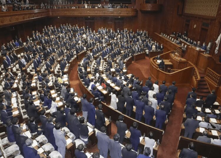 Japanese lawmakers stand as they approve a contentious awareness promotion bill for LGBTQ+ rights at the lower house in Tokyo Tuesday, June 13, 2023.