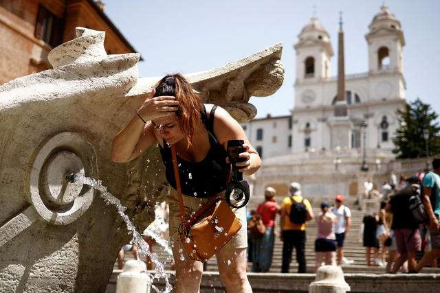 A woman cools off at Fontana della Barcaccia at the Spanish Steps in Rome Italy during a heat wave across southern Europe