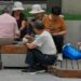 Adults play cards on a bench as a child plays with a smartphone.