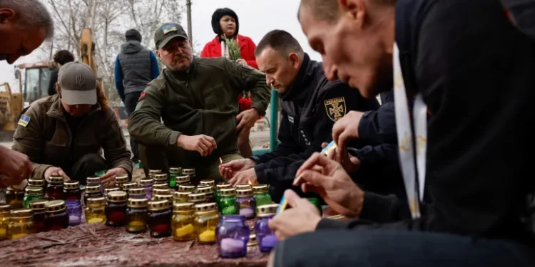 People light candles and lay flowers, paying tribute on October 6, 2023, to the victims of a Russian military strike on a village in the Kharkiv region.