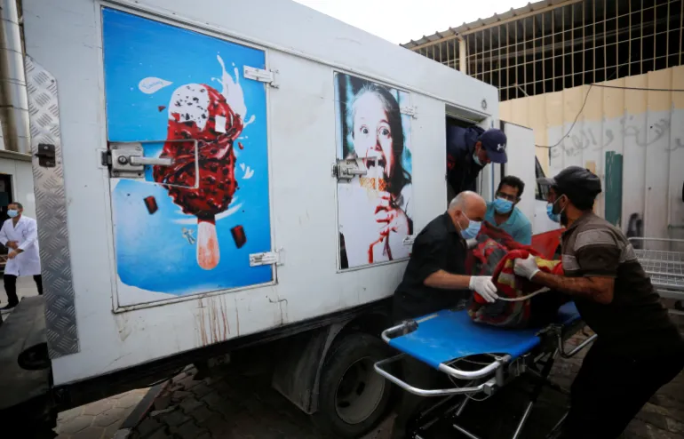 Hospital workers move the body of a Palestinian who was killed in Israeli air raids from an ice cream truck where it was kept as the hospital morgues are packed