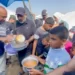 Aid Trucks Labelled As Crumbs 11 A Volunteer cook ladles a serving to the huddle of mostly children, who are holding out metal bowls and pots in their outstretched hands.