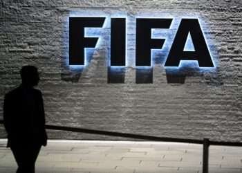 A FIFA employee walks past a sign of the FIFA at the headquarters on December 3, 2015 in Zurich.