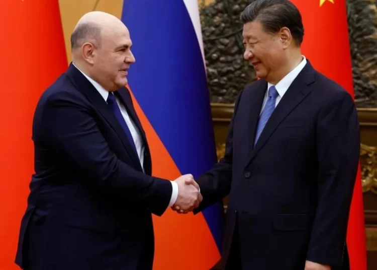 Russian Prime Minister Mikhail Mishustin (L) and Chinese President Xi Jinping shake hands before their meeting Wednesday in Beijing.