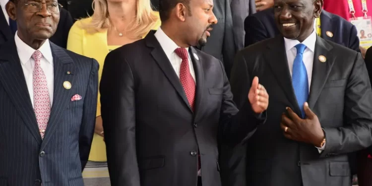 Kenya's President William Ruto talks to Ethiopian Prime Minister Abiy Ahmed as President Teodoro Obiang Nguema Mbasogo of Equatorial Guinea looks on at the 19th summit of the Non-Aligned Movement (NAM) in Kampala, Uganda, on January 19, 2024.