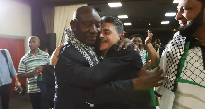 South African president Cyril Ramaphosa and the deputy ambassador of Palestine, Bassam Elhussiny hug as they watch the ICJ ruling on the emergency measures requested by South Africa against Israel over its war on the Gaza Strip, in Johannesburg.