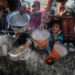 Palestinian children wait in line to receive food prepared by volunteers for Palestinian families displaced to Southern Gaza due to Israeli attacks, between rubble of destroyed buildings in Rafah, Gaza, on February 9, 2024.