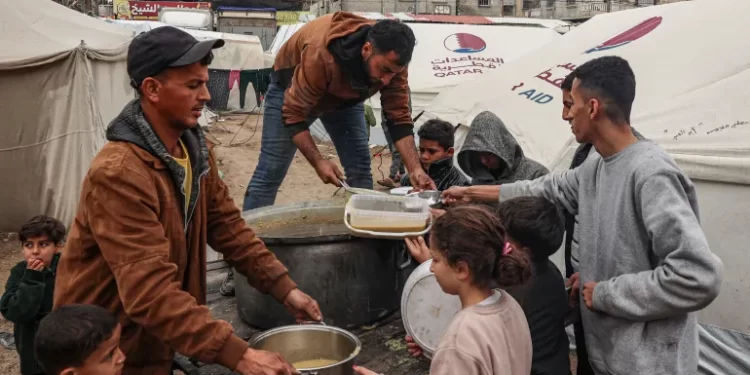 Volunteers distribute rations of red lentil soup to displaced Palestinians in the southern Gaza Strip on February 18, 2024.