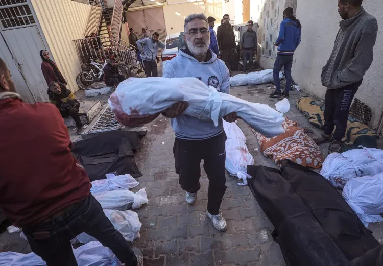A man carries the body of a child killed by an Israeli air strike in Al Nusairat refugee camp.