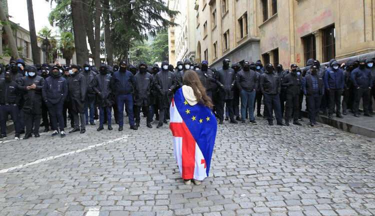 Georgia Parliament Approves Foreign Agents Bill 1 A protester, draped with Georgian national and European Union flags, stands before police officers blocking the way to the country's parliament building on Tuesday, May 14, 2024.