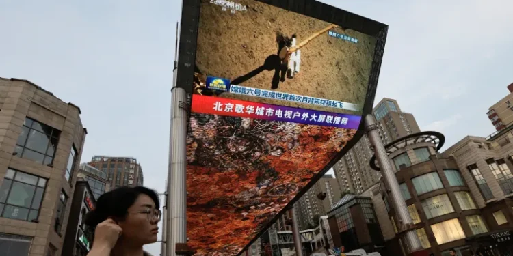 A large screen shows news footage of China's Chang'e-6 lunar probe collecting a sample from the far side of the moon, in Beijing, China, on June 4, 2024.