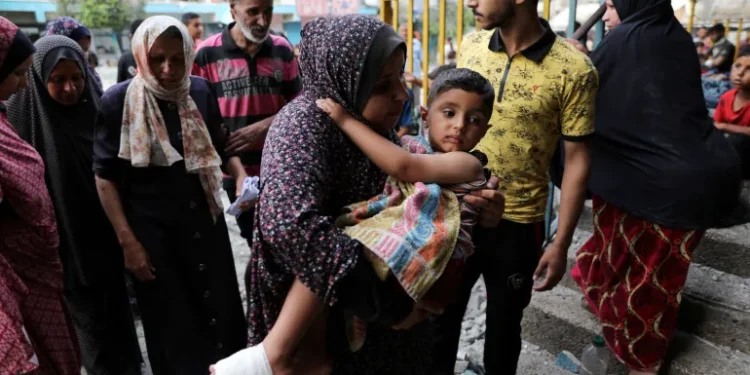 A Palestinian woman carries a child at the site of an Israeli attack on a UN school sheltering displaced people in Nuseirat refugee camp in the central Gaza Strip, June 6, 2024.