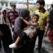 A Palestinian woman carries a child at the site of an Israeli attack on a UN school sheltering displaced people in Nuseirat refugee camp in the central Gaza Strip, June 6, 2024.