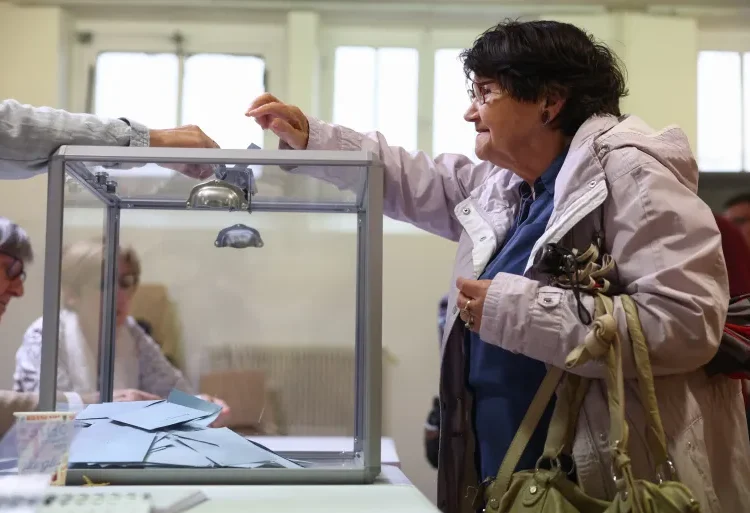 Historic Voter Turnout In France’s Snap Parliamentary Election 1 A woman casts her ballot at a polling station in Tulle, France.