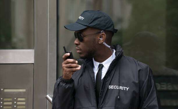 Young African Male Security Guard Talking On Walkie-Talkie