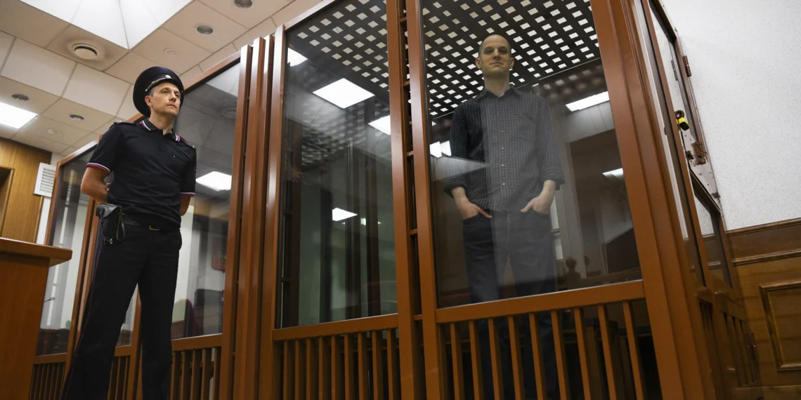 Wall Street journal reporter, Evan Gershkovich stands in a glass cage in a court room in Yekaterinburg, Russia.