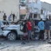 A group of people look at the debris and destruction at a cafe in Mogadishu following a car bomb blast