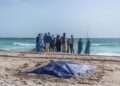Bystanders look at covered bodies of migrants who perished in a shipwreck off the coast of Mauritania