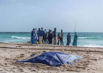 Tragic Shipwreck Shows Perils of Migrant Journeys 2 Bystanders look at covered bodies of migrants who perished in a shipwreck off the coast of Mauritania
