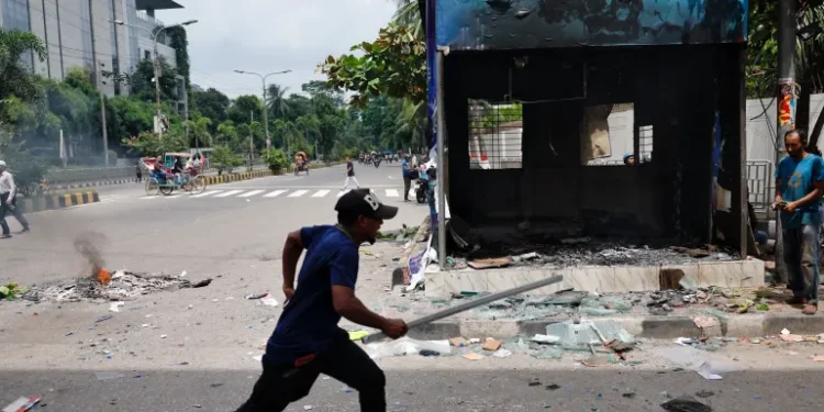 A demonstrator runs next to a vandalised police box in Dhaka.