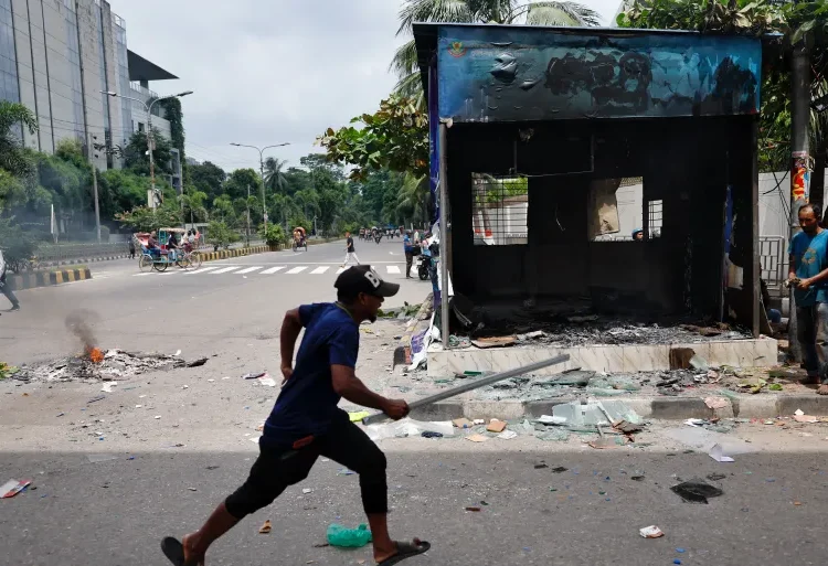 A demonstrator runs next to a vandalised police box in Dhaka.