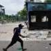 A demonstrator runs next to a vandalised police box in Dhaka.