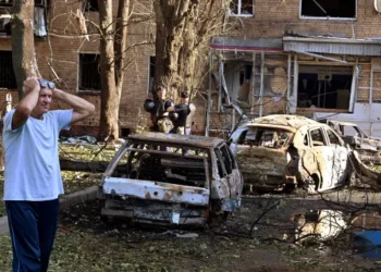 A man reacts while standing next to burnt-out remains of cars in the courtyard of a multi-storey residential building in Kursk, Russia.