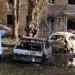 A man reacts while standing next to burnt-out remains of cars in the courtyard of a multi-storey residential building in Kursk, Russia.