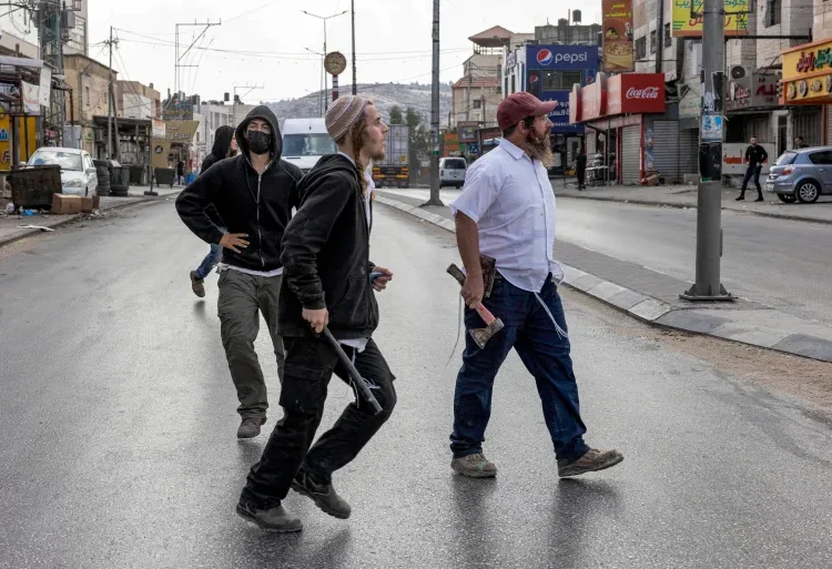 UN Records Surge In Israeli Forces Killing In Occupied West Bank 1 Israeli settlers walk with batons and axes along a street as Palestinian residents and shops were attacked in the town of Huwara in the occupied West Bank.