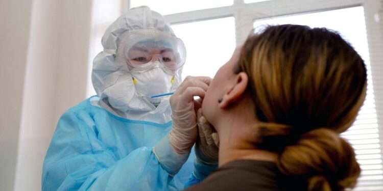 COVID-19 Surge Threatens Global Health Stability 1 A woman is tested for COVID-19