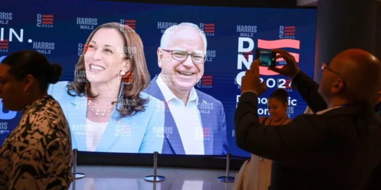 People stand in front of a sign featuring Democratic presidential candidate, Vice President Kamala Harris and Democratic Vice presidential candidate, Minnesota Gov. Tim Walz before the start of the Democratic National Convention in Chicago.