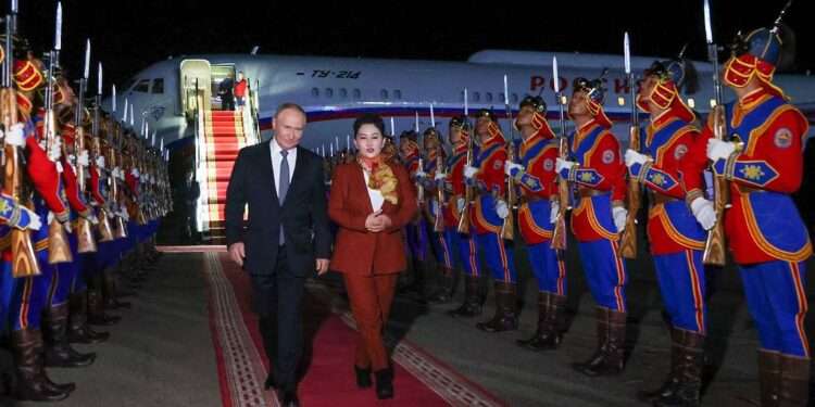 Russia's President Vladimir Putin, accompanied by Battsetseg Batmunkh, Mongolia's Minister of Foreign Affairs, walks past honour guards upon arrival at the airport in Ulaanbaatar.