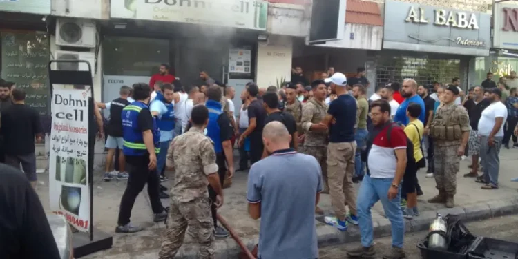 People and first responders gather at the scene of a reported device explosion in Saida in southern Lebanon.