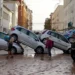 Residents walk past piled up cars following deadly floods in Valencia's De La Torre neighbourhood, south of Valencia.