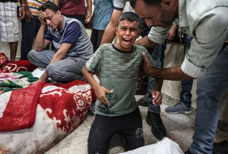 Child cries as bodies of Palestinians are brought to al-Awda Hospital after an Israeli attack.