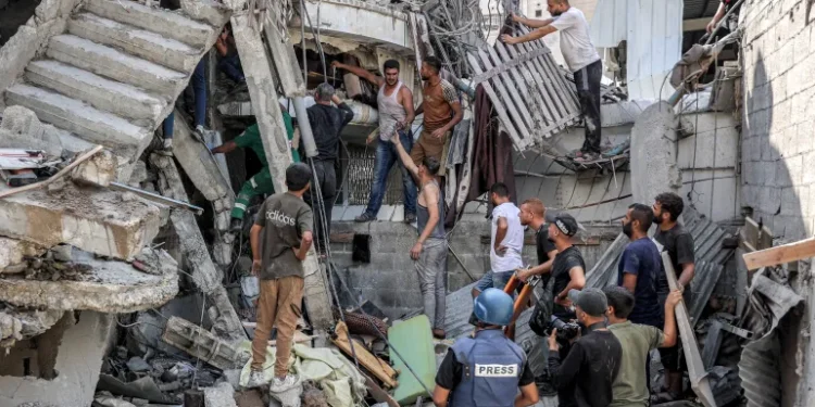 Israel’s Assault On Gaza Escalates To Horrifying Level 1 People gather outside a collapsed building as they attempt to extricate a man from underneath the rubble following an Israeli bombardment in the as-Saftawi district in Jabalia in the northern Gaza Strip.