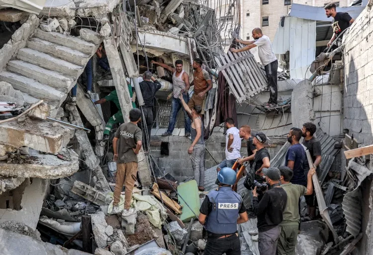 Israel’s Assault On Gaza Escalates To Horrifying Level 1 People gather outside a collapsed building as they attempt to extricate a man from underneath the rubble following an Israeli bombardment in the as-Saftawi district in Jabalia in the northern Gaza Strip.