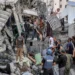 People gather outside a collapsed building as they attempt to extricate a man from underneath the rubble following an Israeli bombardment in the as-Saftawi district in Jabalia in the northern Gaza Strip.