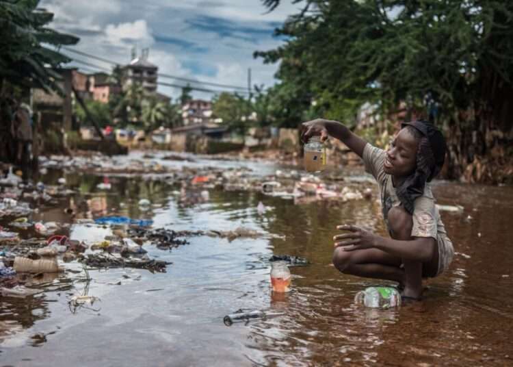 A child sitting in a  Garbage dump