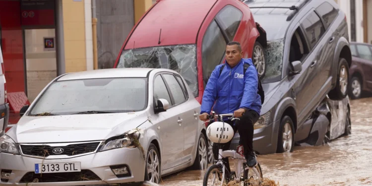 A man rides a bicycle through flooded streets in Valencia, Spain.