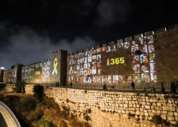 Fate Of Remaining Captives Contingent On Israel’s Actions 2 People walk by the walls of Jerusalem’s Old City as pictures of people taken captive during the October 7 attack on Israel are projected on them.