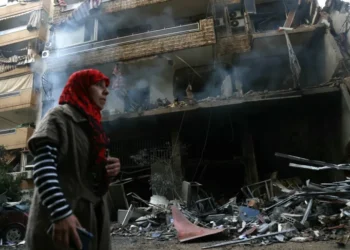 A woman walks past a building damaged by Israeli airstrikes on Tayouneh in Beirut's suburban outskirts.