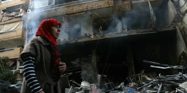 A woman walks past a building damaged by Israeli airstrikes on Tayouneh in Beirut's suburban outskirts.