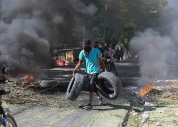 UN Evacuates Staff Amid Escalating Violence in Haiti 3 A resident carries tyres to be added to a burning barricade to deter gang members from entering his neighbourhood, in Port-au-Prince, Haiti, Tuesday, November 19