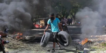 A resident carries tyres to be added to a burning barricade to deter gang members from entering his neighbourhood, in Port-au-Prince, Haiti, Tuesday, November 19
