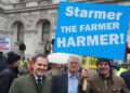 Robert Jenrick poses under a ‘Starmer the farmer harmer’ banner