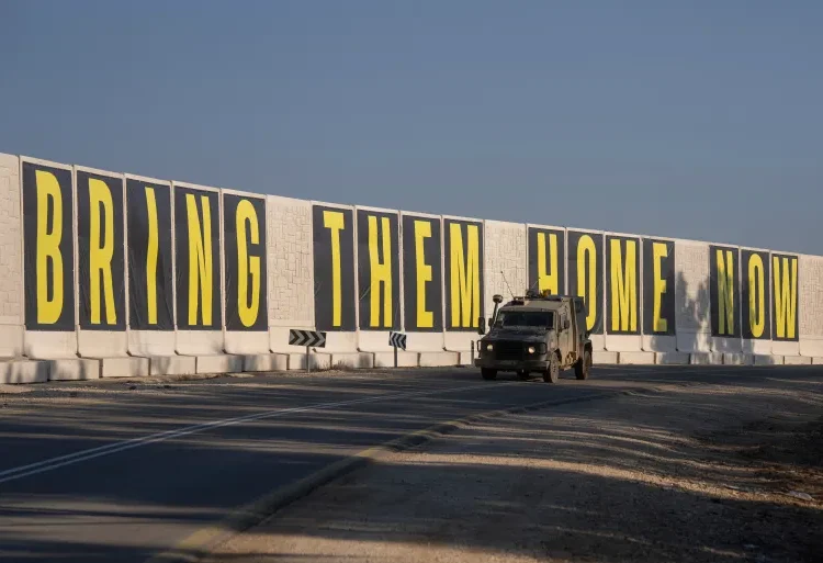Hope Ignited For Gaza Ceasefire 1 An israeli army vehicle near the Israeli-Gaza border, drives beside a banner reading ” Bring them home now” call for the release of hostages held in the Gaza Strip.